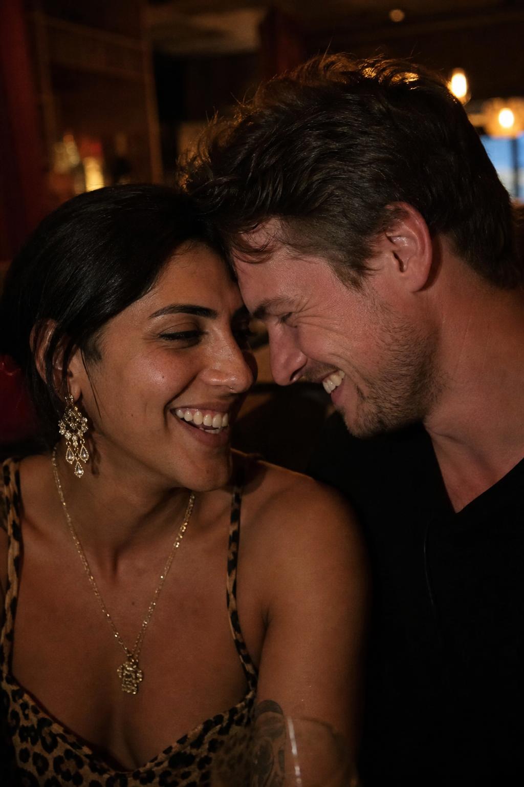 Couple laughing together on a date in a dimly lit bar